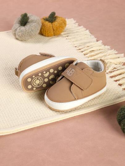 一双印有字母图案的男婴运动鞋，采用魔术贴搭扣设计，百搭运动鞋，适合春秋季穿着。