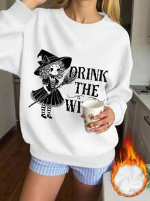 A imagem principal do produto apresenta uma bruxa com chapéu e vestido pretos segurando uma vassoura. O texto diz "Beba o vinho" em uma fonte elegante. O fundo é azul sólido sem elementos adicionais. O design é centralizado na frente do moletom, destacando a bruxa e o texto ousadamente "A bruxa tem meias listradas e"