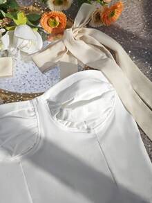 Top corto de mujer de un solo pieza, con diseño elegante y casual, hombros descubiertos, sin mangas, con detalles de lazo y silueta que favorece la figura