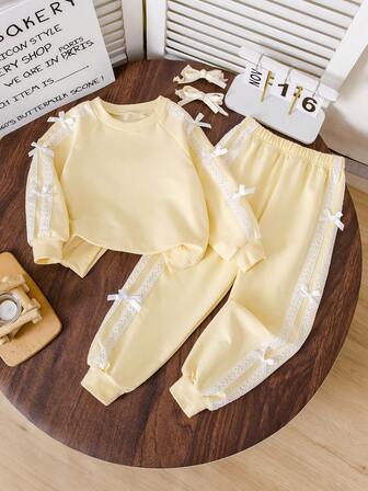 Cremefärgad gul rosett-tröja för små flickor. Mjukt och bekvämt tröjmaterial, rund halsringning, långärmad tröja och byxor. Rosettdesign på ärmar och byxfållar, sött för vardagsbruk, tillbaka till skolan, vardagliga utflykter, höst/vinter