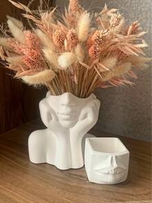 O vază cu design artistic, în formă de femeie cu mâinile care îi cuprind fața. Este simplă, dar elegantă, cu un design unic și fermecător în formă de față cu mâinile. Ideală pentru aranjarea florilor proaspete sau artificiale și poate fi folosită și pentru depozitarea cosmeticelor. Potrivită pentru decorarea camerelor de zi și a dormitoarelor pe tot parcursul anului, un element indispensabil pentru decorul zilnic al casei.