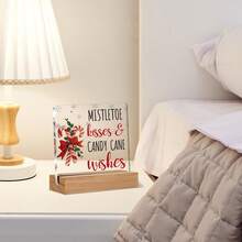 Articole decorative de Crăciun, inclusiv ornamente din acadele pentru casă, sărutări și urări cu tematică de vâsc, afișate pe semne și plăcuțe de birou din acril.