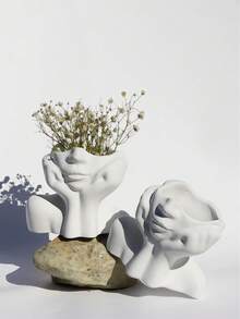 O vază cu design artistic, în formă de femeie cu mâinile care îi cuprind fața. Este simplă, dar elegantă, cu un design unic și fermecător în formă de față cu mâinile. Ideală pentru aranjarea florilor proaspete sau artificiale și poate fi folosită și pentru depozitarea cosmeticelor. Potrivită pentru decorarea camerelor de zi și a dormitoarelor pe tot parcursul anului, un element indispensabil pentru decorul zilnic al casei.