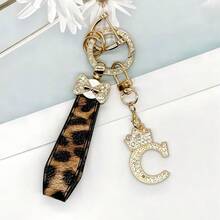 Breloc din aliaj de zinc, 1 bucată, cu design din piele PU imprimată, împreună cu un pandantiv strălucitor cu literă în formă de coroană, strat antirugină, potrivit pentru agățarea cheilor mașinii, cheilor etc. Se potrivește cu orice și este un accesoriu indispensabil pentru a purta!