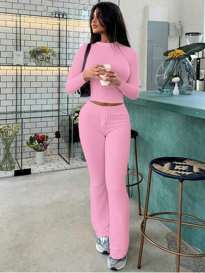Conjunto deportivo de mujer de primavera con top de manga larga que deja ver el abdomen y pantalones acampanados de ajuste ceñido con cordones