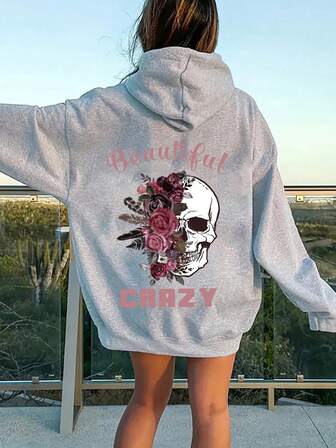 大码女式日常连帽长袖卫衣，白色骷髅头搭配深粉色玫瑰羽毛，粉色字母印有“Beautiful”和“CRAZY”字样，休闲百搭，适合春夏秋季穿着。这款大码女式长袖连帽卫衣，也是感恩节外出、度假等场合的理想之选。