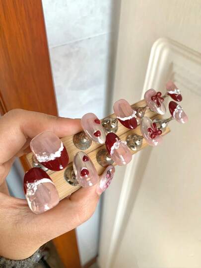 New Year Manicure And Valentine's Day Nail Designs, A Retro, Sweet And Elegant Style. Ten Short Oval Pressed Nails, Handmade. The Overall Color Scheme Is Mainly Soft Pink And Rich Wine Red. Hand-Painted Red And White French Edges. Some Nails Have A Gradient Of Silver Mirror Powder. Paired With Red Bows, Hearts, Pearls, Diamonds, Etc., For A Lively, Exquisite And High-End Fashion Manicure.