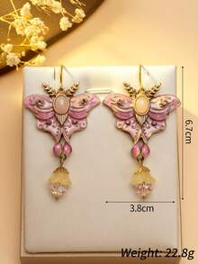 1 对浪漫优雅的蝴蝶耳环。粉紫色的蝴蝶翅膀就像娇嫩绽放的花瓣，散发着柔和的色调。中心的椭圆形宝石就像蝴蝶的眼睛，散发着神秘的光芒。下方的光泽珍珠点缀如晨露般生动。戴上它们，仿佛用春天的辉煌和诗意装饰了你的耳朵。