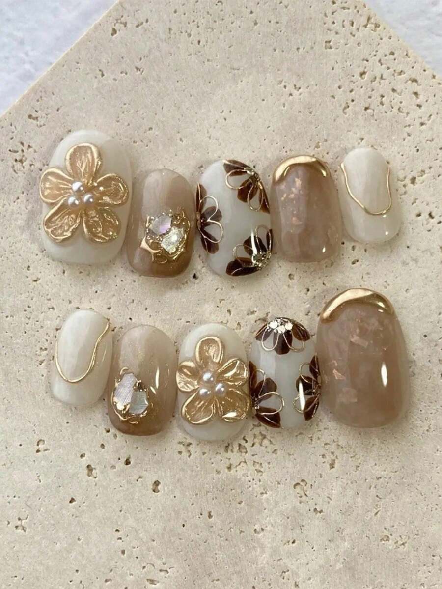 新款秋冬十片装短款椭圆形美甲贴片，日式美甲风格。以暖棕色等柔和色调为底色，搭配精致的金色花朵、线条装饰，以及珍珠和小钻石点缀，不仅散发着复古优雅的魅力，更通过金属质感和闪亮装饰营造出轻盈奢华之感。美甲用品 手工贴片 - Follow Your Heart - 查看 1