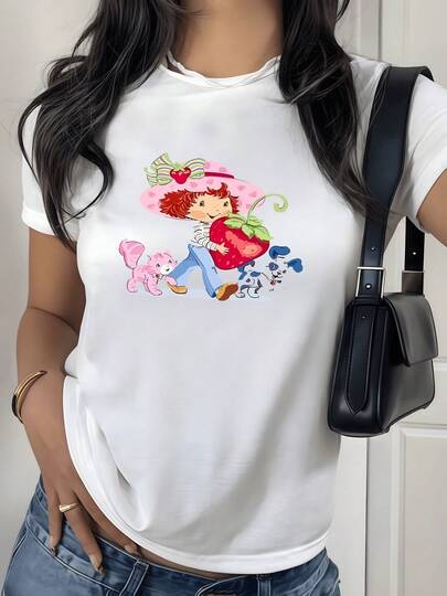 Niña con sombrero rosa sosteniendo gran fresa acompañada de gato y perro en escena alegre camiseta de mujer 100% algodón casual