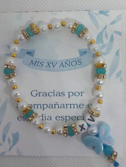 Pulsera para xv años – Recuerdo XV Años  Celebra momentos inolvidables con esta elegante pulsera ideal para XV años. Diseñada con delicadas perlas blancas, cristales verdes y detalles dorados brillantes, esta pieza combina sofisticación y ternura. Su colgante en forma de angelito simboliza protección y buenos deseos, haciendo de esta pulsera un recuerdo único y especial para tus invitados.  Detalles del producto:  Material: Perlas sintéticas, cristales verdes y metal dorado.  Diseño: Incluye un colgante angelito con detalles dorados.  Tamaño: Ajustable, apto para la mayoría de las muñecas.  Ideal para: Recuerdos de XV años, fiestas temáticas y regalos especiales.  Presentación: Incluye bolsa de celofán y tarjeta de agradecimiento personalizada.  Dale un toque elegante y lleno de significado a tu celebración con esta pulsera que tus invitados atesorarán.