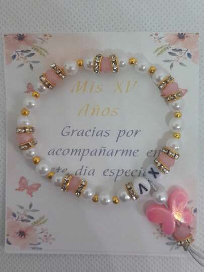 Pulsera para xv años – Recuerdo XV Años  Celebra momentos inolvidables con esta elegante pulsera ideal para XV años. Diseñada con delicadas perlas blancas, cristales verdes y detalles dorados brillantes, esta pieza combina sofisticación y ternura. Su colgante en forma de angelito simboliza protección y buenos deseos, haciendo de esta pulsera un recuerdo único y especial para tus invitados.  Detalles del producto:  Material: Perlas sintéticas, cristales verdes y metal dorado.  Diseño: Incluye un colgante angelito con detalles dorados.  Tamaño: Ajustable, apto para la mayoría de las muñecas.  Ideal para: Recuerdos de XV años, fiestas temáticas y regalos especiales.  Presentación: Incluye bolsa de celofán y tarjeta de agradecimiento personalizada.  Dale un toque elegante y lleno de significado a tu celebración con esta pulsera que tus invitados atesorarán.