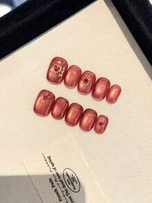 10 Stücke hochwertige und luxuriöse handgefertigte tragbare Nägel mit großen roten Katzenauge-Sternen und Sonnenblumen-Aufklebern. Die gepressten Nägel sind für Frauen, Mädchen und Studenten für den täglichen Gebrauch geeignet. Es sind quadratische Nägel für Partys, Feiern und Einkaufen, die weiß und elegant aussehen. Die kurzen Nägel kommen mit Gelee-Kleber und Reibestreifen als Geschenke.