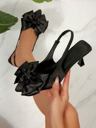 Svarta högklackade skor med bakre rem, spetsig tå, rosettdekor, satin, resårband, moderiktiga högklackade skor, eleganta, charmiga, sexiga, ihåliga dampumps, kitten heels