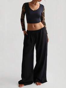 A Women's Black Cropped Top With A V - Neckline, Adorned With Sheer Black Floral Lace Long Sleeves That Bring A Delicate Touch, Made Of Smooth Fabric To Craft A Sexy Yet Elegant Overall Look.