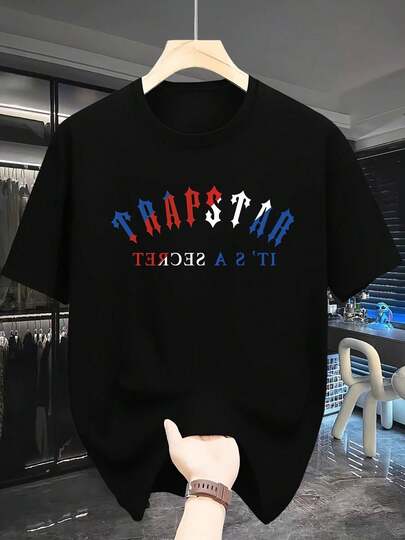 La inscripción audaz TRAPSTAR en la parte superior con letras rojas blancas y azules refleja una actitud de confianza y rebeldía. Debajo, la frase en espejo IT'S A SECRET añade un toque enigmático a camiseta de hombre.