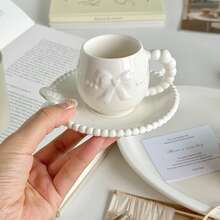 A Set Of Ceramic Coffee Cups And Saucers With Bow-Tie Relief Design (100-180ml Capacity). Perfect For Home Kitchens, Dining Rooms, Or Living Spaces. Each Cup Comes With A Matching Saucer. Ideal For Serving Tea, Coffee, Milk, Water, Or Juice. Suitable For Outdoor Use, Weddings, Parties, Gifting, Or Birthdays.