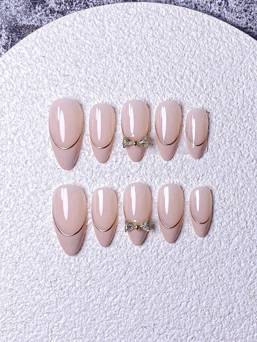 10片手工法式短指甲贴纸。这款美甲套装包含5种颜色：白色、粉色、金色、蓝色和黄色，设计迷人可爱。每张指甲贴纸都饰有手绘藤蔓图案，沿着金属法式边缘蜿蜒而下，并点缀着金色和钻石蝴蝶结。 - 粉色 - 查看 1