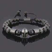 Descubre la Pulsera de Lujo para Hombre con Casco Gladiador Dorado, una joya moderna que combina la fuerza del estilo masculino con la sofisticación del diseño contemporáneo. Cada detalle ha sido cuidadosamente elaborado para reflejar poder, elegancia y exclusividad.  Su diseño incorpora cuentas metálicas en tono dorado de alta calidad, finamente texturizadas para aportar brillo y distinción, junto a piedras negras pulidas que realzan su carácter imponente. En el centro, un casco de guerrero con incrustaciones brillantes simboliza la determinación, liderazgo y lujo atemporal.  Ajustable y cómoda,  se adapta perfectamente a la muñeca, convirtiéndose en el accesorio ideal para hombres con estilo y personalidad. Ideal tanto un look formal como uno casual, siempre aportando un toque de elegancia refinada y moda exclusiva.  Ideal como regalo, esta pulsera es el detalle perfecto para cumpleaños, aniversarios o celebraciones especiales, transmitiendo buen gusto, distinción y fuerza interior. - Negro - Ver 8