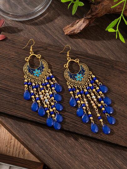 Un par de pendientes de estilo bohemio retro con patrones tallados y detalles de gota de aceite, borlas en forma de lágrima hechas de cuentas de semillas. Adecuado para que las damas lo usen durante las celebraciones de festivales.