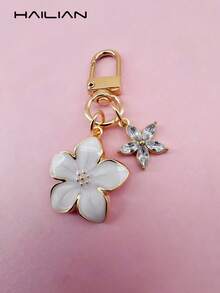 HAILIAN 这款轻巧优雅的樱花造型钥匙扣采用合金材质，专为女性设计，配有六瓣小花挂饰。作为旅行配件，它既可作包包挂饰，也可作车钥匙扣，更是情侣生日和节日的理想礼物。 - 白色 - 查看 3