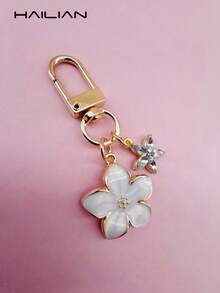 HAILIAN 这款轻巧优雅的樱花造型钥匙扣采用合金材质，专为女性设计，配有六瓣小花挂饰。作为旅行配件，它既可作包包挂饰，也可作车钥匙扣，更是情侣生日和节日的理想礼物。 - 白色 - 查看 4