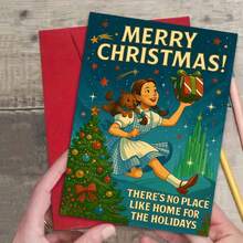 Urzekający plakat świąteczny z Czarnoksiężnikiem z Krainy Oz przedstawiający Dorotkę i Toto z świątecznym prezentem na tle panoramy Szmaragdowego Miasta – "Nie ma jak w domu na święta" Nostalgiczna sztuka ścienna z udekorowaną choinką i migoczącymi gwiazdami - wielobarwność - Zobacz 4