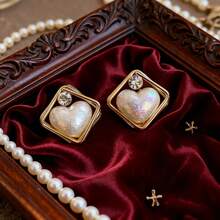 Un par de elegantes y sencillos pendientes de perlas con forma de corazón y marco dorado hipoalergénico. Su diseño de moda, único, ligero y delicado los convierte en una opción ideal para mujeres, adecuados para uso diario, fiestas, bodas y todas las estaciones. Estos pendientes no solo son un accesorio encantador, sino también un toque final perfecto para una fiesta, un adorno elegante y único, y un regalo maravilloso para las mujeres.