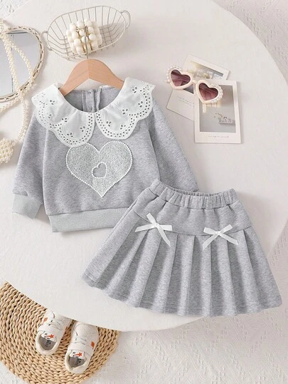 Söt långärmad tröja med hjärtmönster och krage för små flickor, i kombination med enfärgad plisserad kjol med 3D-rosett, 2-delat moderiktigt set för små flickor, lämplig för vardag, fest och utflykter på hösten/vintern