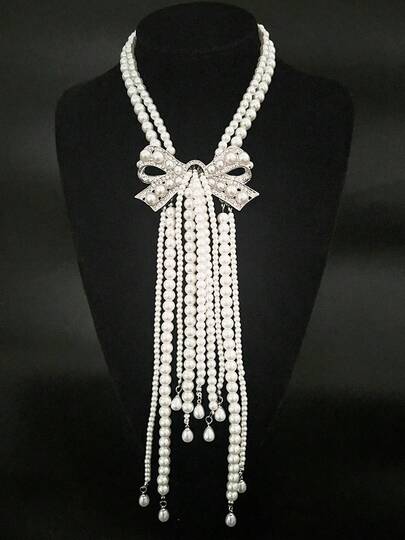 Diese zweireihige Kunstperlenkette mit Schleife und Quaste lässt sich vielseitig kombinieren – ob zu eleganten Kleidern, Anzügen oder Pullovern – und ist somit für jede Jahreszeit geeignet. Sie ist auch ein ideales Geschenk, um jedem Outfit Eleganz und Raffinesse zu verleihen.