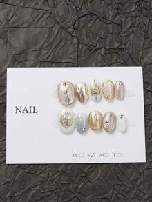 10片手工制作的闪亮亮片，饰以迷人的月亮和星星图案，神秘而奢华。以白色和米色为主色调，点缀金色和银色，轻松搭配任何服饰，让您更加闪耀。美甲用品 - 香檳色 - 查看 5