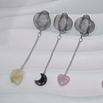 这款304不锈钢茶球滤茶器饰有天然水晶石和月牙形水晶装饰，是冲泡红茶和绿茶等饮品的绝佳伴侣。它配有多种水晶，包括紫水晶、粉晶和黄水晶，这些水晶被加工成不同的形状，例如天然原石、月牙形和心形。