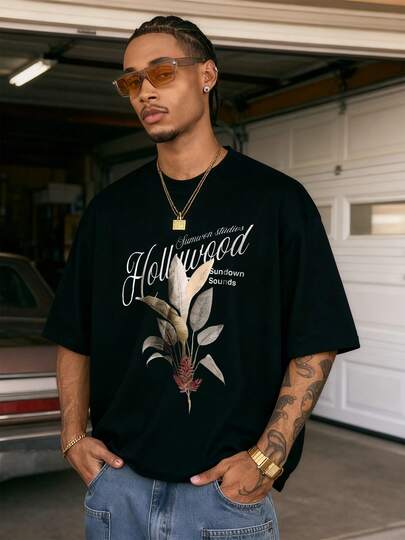 Exquisito follaje tropical con hojas en tonos naturales arena y oliva el icónico  Sunwon studios y Sundown Sounds evoca una elegancia retro cinematográfica para una camiseta de hombre 100% algodón premium