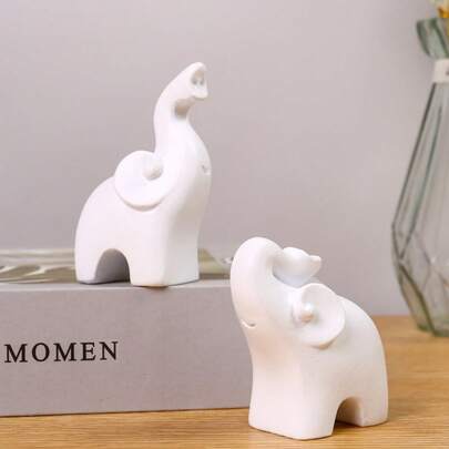 一套（2个），这款现代简约风格的大象摆件采用白色树脂精制而成，工艺精湛。适用于各种环境，与现代美学相得益彰，是家居摆设、办公室装饰、展厅布置和艺术点缀的理想之选。