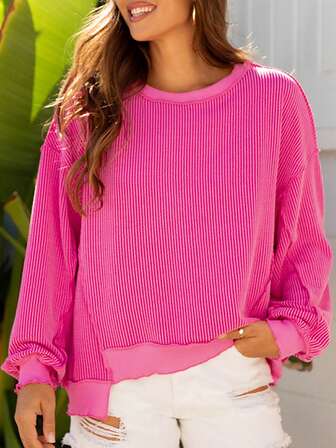 Top holgada de punto con hombros caídos, bajo desigual y costilla retorcida de color rosa fresa