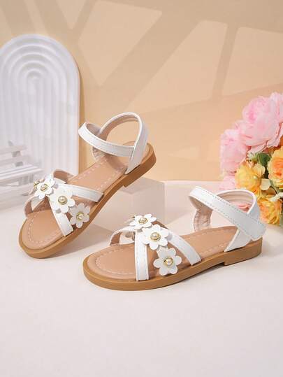 一双女童凉鞋，饰有立体花朵珍珠，采用PU皮革制成，穿着舒适，行走方便，露趾低帮设计，配有绑带，平底款式，甜美公主风凉鞋，适合夏季派对和日常出行。