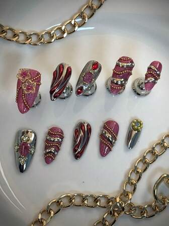 10片手工制作的杏仁粉色猫眼美甲贴片，银色、红色可选，非常适合秋冬季节。它们采用3D立体花卉雕刻，饰有不对称的金色液体条纹，并点缀着金色钢珠和宝石。这些亚克力美甲贴片非常适合派对、婚礼和日常佩戴，是送给女性和女孩的绝佳礼物。