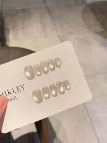 10 片手工制作的美甲贴片，品质上乘，简约而高端，饰有闪亮的玻璃珠、猫眼、碎钻和短款美甲贴片。每片美甲贴片均配有果冻胶和固定条。