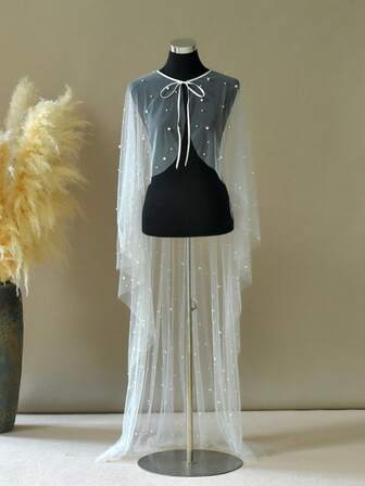 这款饰有珍珠的女士披肩，采用柔软的薄纱制成，并配有系带，散发着法式优雅，是搭配婚纱的完美之选。