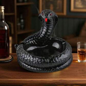 这款创意蛇形烟灰缸，采用黑色蛇身设计，配以栩栩如生的红眼蛇头细节。盘绕的蛇身构成烟灰收集区，为空间增添独特而引人注目的点缀。蛇身凹槽可放置烟头，内部空间用于收集烟灰，满足吸烟场景的实用需求。适合放置于桌面、客厅茶几、办公室等场所，作为一件“创意摆件”，彰显个性品味。