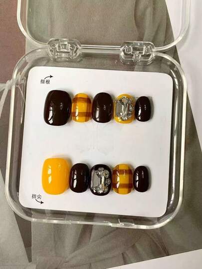 十片短圆美甲贴片。这是新款秋冬款式，采用复古奢华的现代风格。纯手工制作，以极具复古感的焦糖棕色和亮黄色为主色调，搭配格子图案，复古魅力十足。点缀的大颗水晶水钻更添轻盈奢华与优雅。
