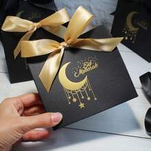 10个黑色礼品袋，饰有金色箔纸月亮和星星图案，优雅的丝带系带包装，适用于开斋节庆祝活动、斋月聚会、派对回礼和节日送礼，适合盛放椰枣、零食、小饰品和纪念品，采用优质纸板制成，时尚装饰袋，适用于家庭聚会、清真寺活动、社区派对和节日礼品展示。 - 11.5X4.5X10cm - 查看 7