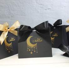 10个黑色礼品袋，饰有金色箔纸月亮和星星图案，优雅的丝带系带包装，适用于开斋节庆祝活动、斋月聚会、派对回礼和节日送礼，适合盛放椰枣、零食、小饰品和纪念品，采用优质纸板制成，时尚装饰袋，适用于家庭聚会、清真寺活动、社区派对和节日礼品展示。 - 11.5X4.5X10cm - 查看 2