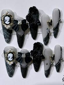 Bộ 10 móng giả thủ công hình hạnh nhân màu đen kiểu Gothic ngọt ngào và cá tính, họa tiết hoa trà Baroque, ren quyến rũ và nơ 3D màu đen, điểm xuyết ngọc trai và các họa tiết trang trí sang trọng. Hoàn hảo cho mọi dịp hàng ngày, dự tiệc, lễ hội, hẹn hò, cô dâu của phái nữ. Tặng kèm 1 keo dán móng + 1 dũa móng. Móng giả thủ công. - màu đen - Xem 13