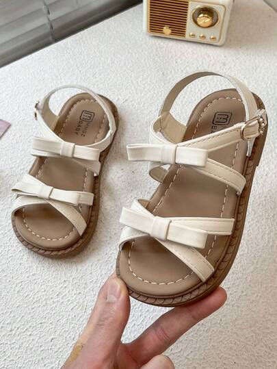 Un par de nuevas sandalias para niños con diseños de lazos y correas y diseños de hebillas metálicas que añaden un toque de refinamiento. Son elegantes y lindas, adecuadas para escenarios diarios y festivos de los niños, e ideales para niños de 3 a 12 años.