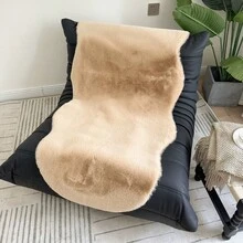 1件仿毛皮米色不对称造型沙发垫，可用作床边垫、躺椅垫。毛绒柔软，高密度聚酯纤维填充。适用于客厅沙发、床边等多种场所。