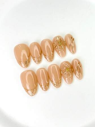 10片中号椭圆形美甲贴片，裸粉色柔和优雅底色，金色3D图案装饰，3D花朵造型（点缀小水钻）及金色线条元素设计，闪亮亮片，100%纯手工制作，可重复使用，适合女性日常或派对佩戴。