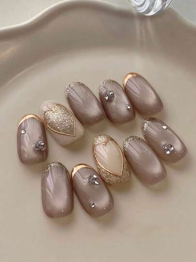 10片椭圆形裸色美甲贴纸，饰有爱心、猫眼和金色镶边法式图案，适合日常佩戴和节日装饰。这些可爱的美甲贴纸可重复使用，是女性和女孩的理想之选。