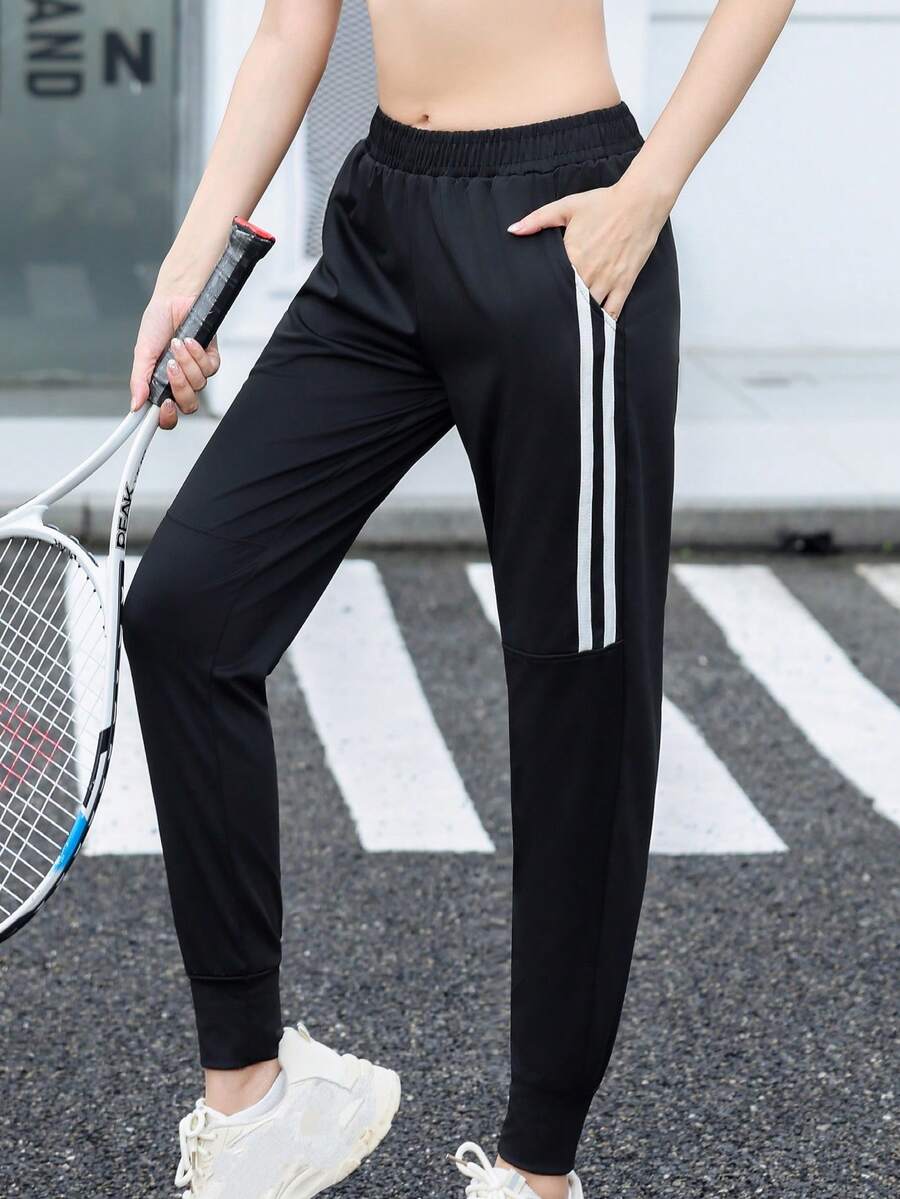 Calça de corrida feminina de cintura alta, com bolsos inclinados, modelo minimalista de cor sólida e corte afunilado, com listras pretas e brancas e cintura elástica. - Preto e Branco - Ver 1