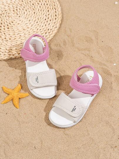 Ett par barnsandaler med dubbla kardborreband för sommaren 2025 – rosa och vit design, avslappnade, moderiktiga, bekväma och enkla. De är ett utmärkt val för vardagsutflykter, skolliv, shopping i köpcentra och sommarlov, och kan enkelt matchas med alla typer av barnkläder.